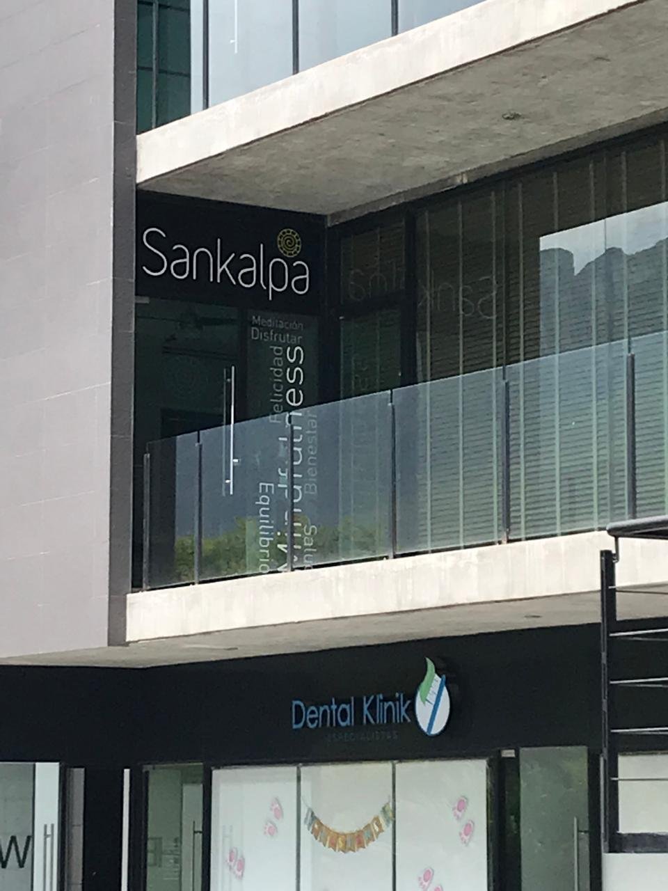 Modern multi-story building facade with Sankalpa sign on upper level and Dental Klinik storefront on ground floor