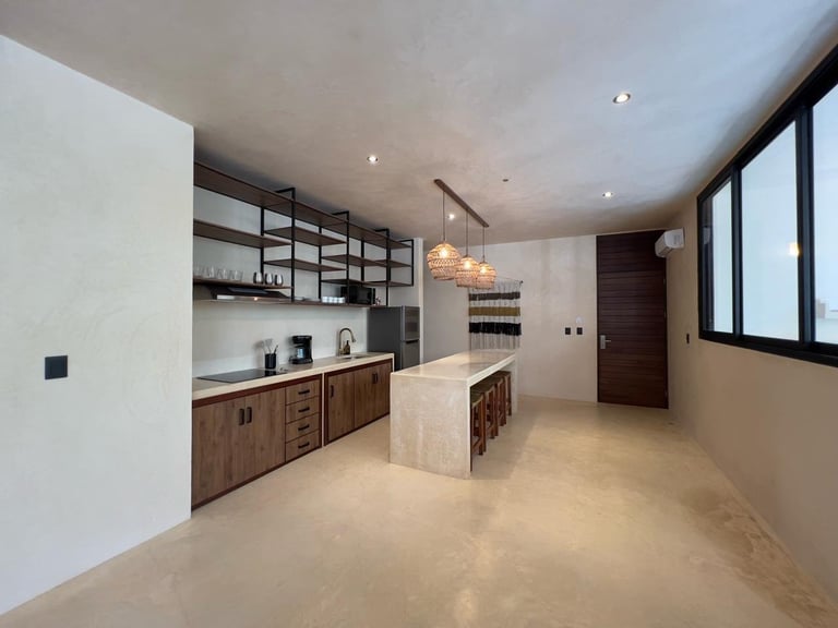 Modern kitchen interior with wooden cabinetry, white countertops, central island, open shelving, and large windows
