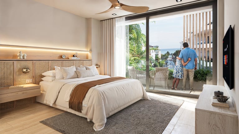 Modern bedroom with queen bed, wooden accents, floor-to-ceiling glass doors opening to a balcony overlooking city and trees
