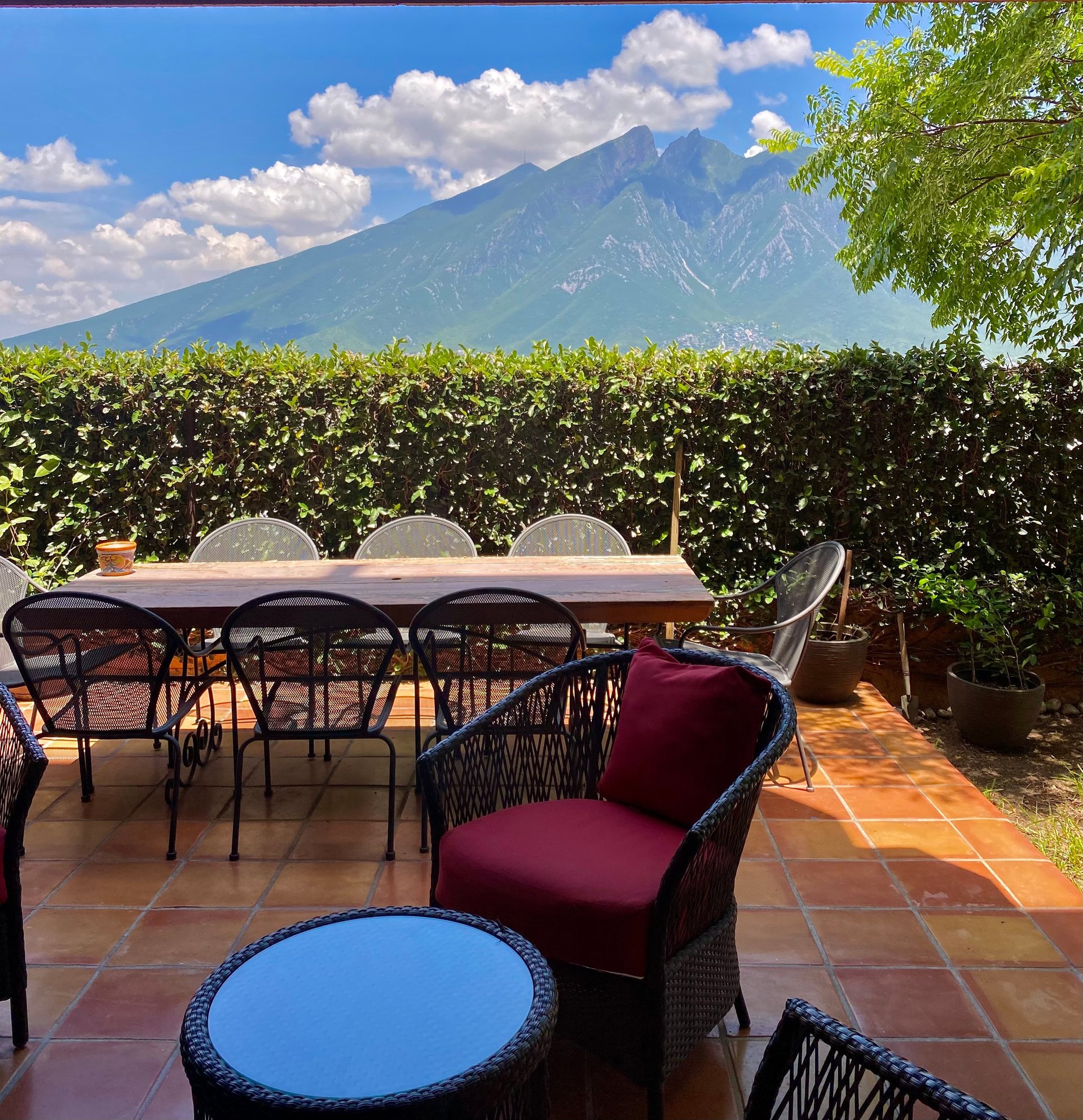 Outdoor patio with dining furniture and mountain view of volcanic peak in background under blue sky with clouds