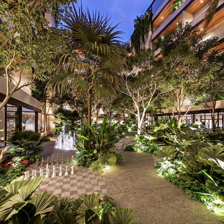 Illuminated courtyard at night with tropical plants, palm trees, and modern building architecture featuring a checkerboard floor