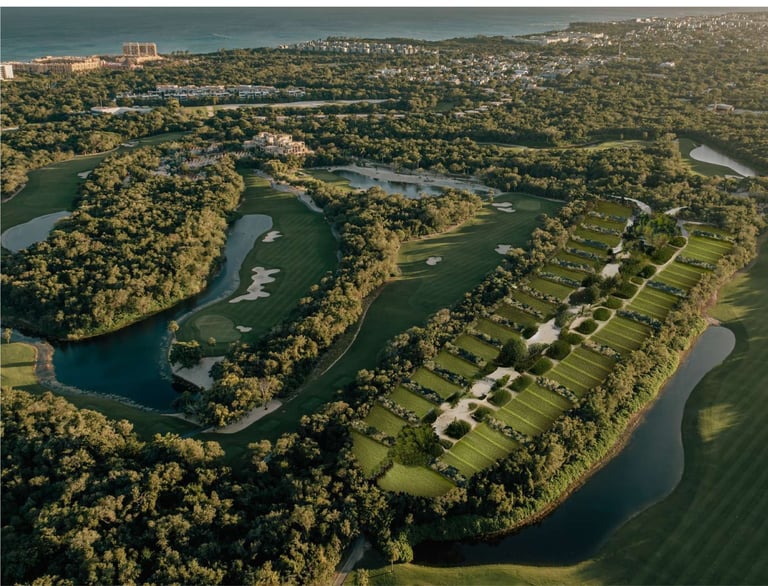 Aerial view of a golf course with fairways, greens, and water hazards surrounded by dense forest and residential areas