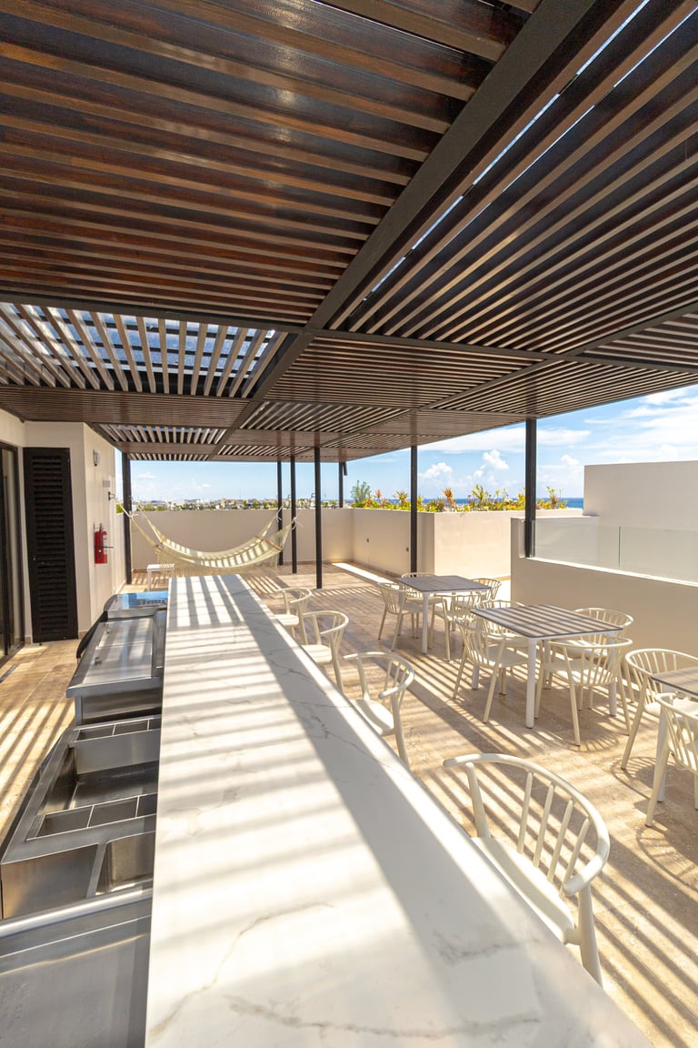Modern rooftop terrace with wooden pergola, dining chairs, hammock, and skyline view on sunny day