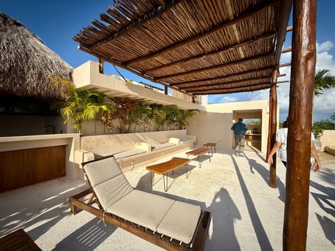 Modern rooftop terrace with wooden pergola, lounge chairs, and ocean view under clear blue sky