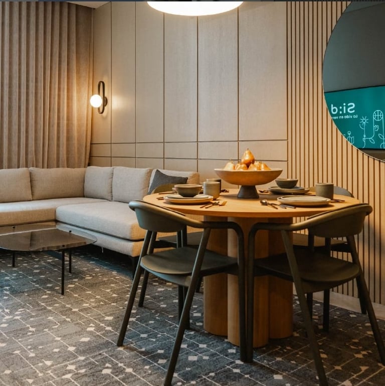 Modern dining area with wooden table and black chairs beside beige sofa under pendant lighting in contemporary interior