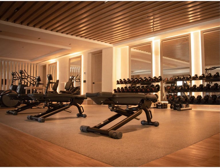 Modern fitness gym interior with free weights, dumbbells on racks, exercise equipment, wooden flooring, and ambient lighting