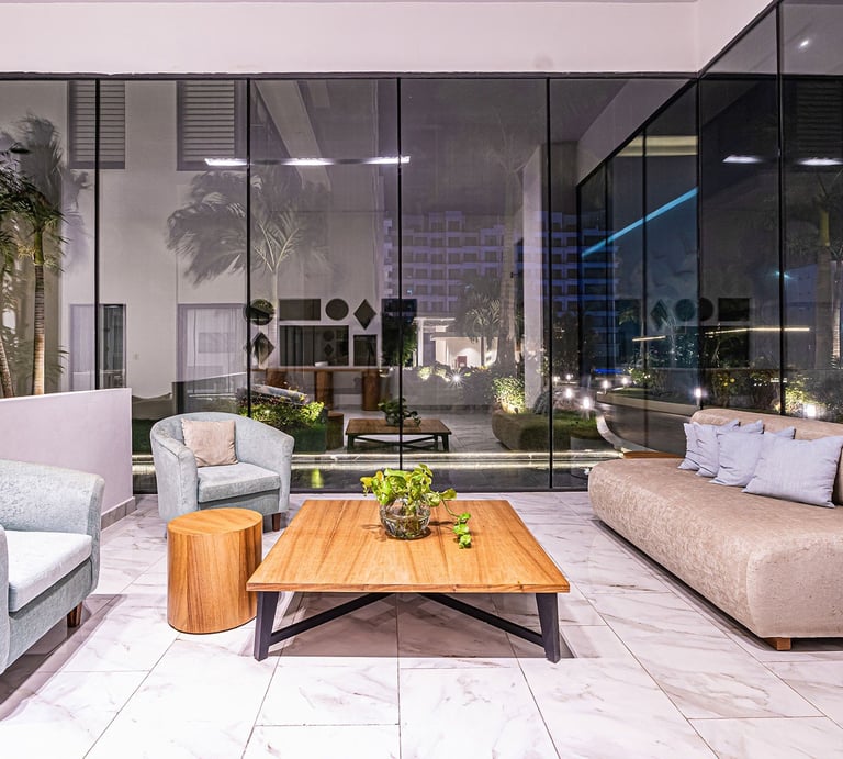 Modern high-rise apartment living room with floor-to-ceiling windows overlooking city skyline, featuring contemporary furniture and wooden coffee table