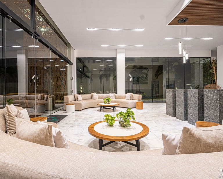 Modern luxury lobby with beige seating areas, round wood coffee table, pendant lighting, and floor-to-ceiling windows