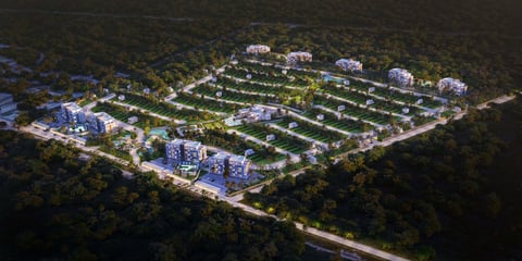 Aerial night view of a residential development with organized street grid, modern buildings, and landscaping surrounded by forest